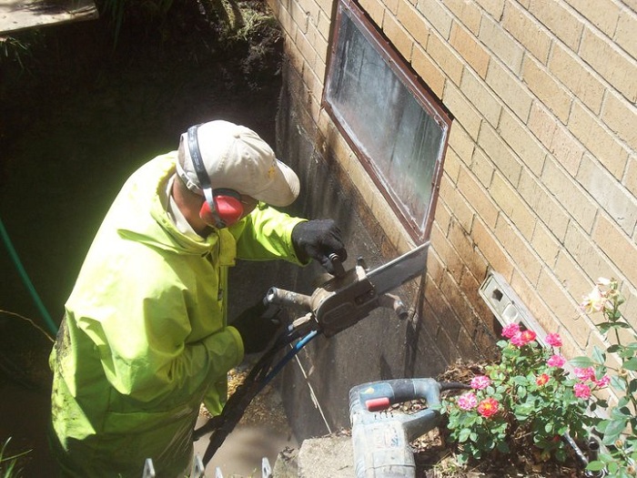 Cut egress window hole in basement wall with hydraulic powered